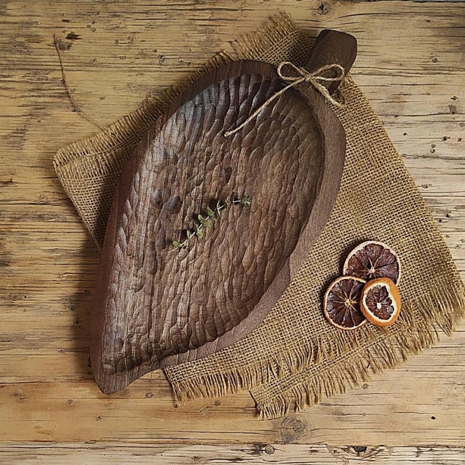 Handgehämmerte Walnussholz-Schale in Blattform mit Griff, auf Juteunterlage mit Trockenfrüchten und Holzdeko