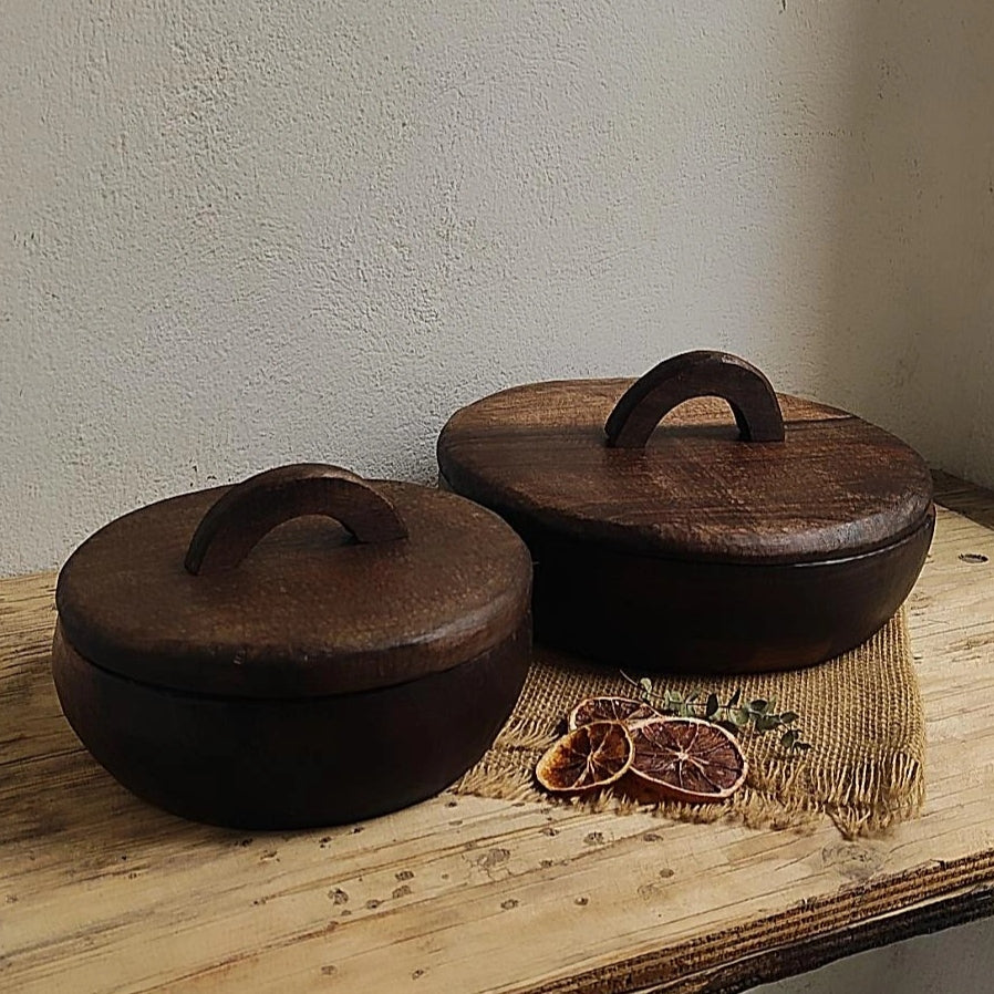 Zwei handgefertigte runde Holzboxen mit Deckel und Griff, auf rustikalem Holztisch mit Trockenfrüchten dekoriert