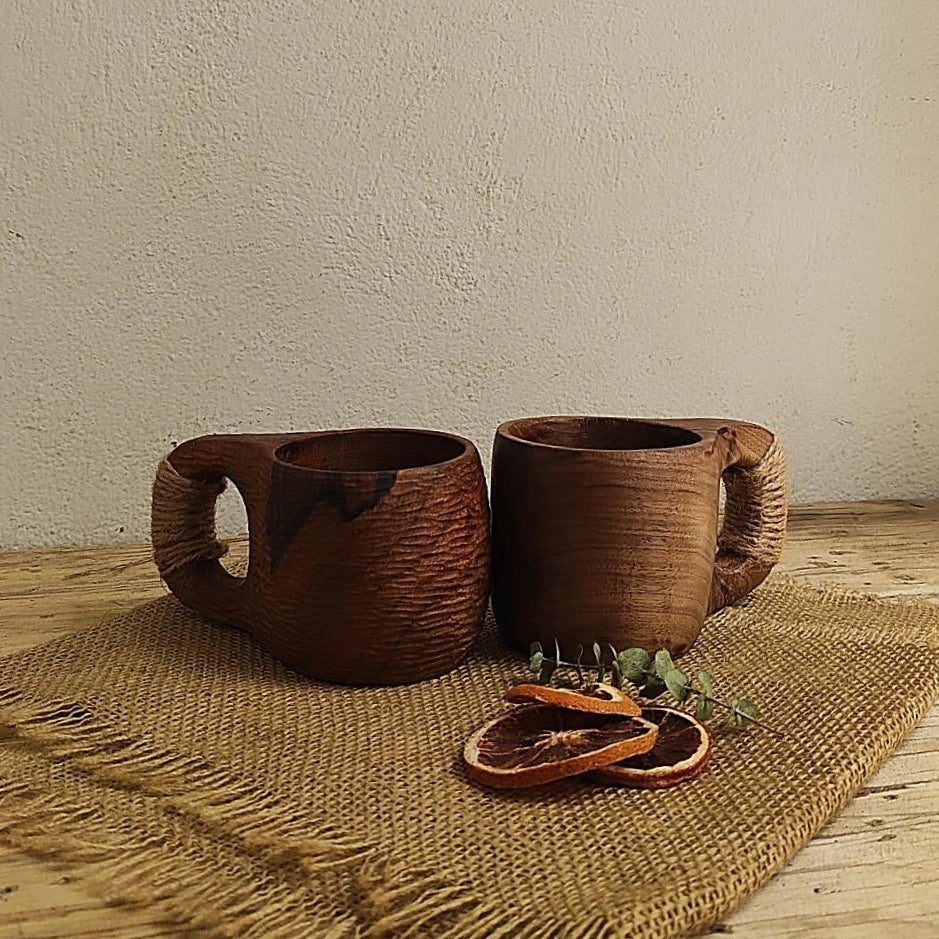 Handgefertigter Becher aus dunklem Walnussholz mit rustikalem Griff, dekoriert mit Trockenfrüchten auf Jute